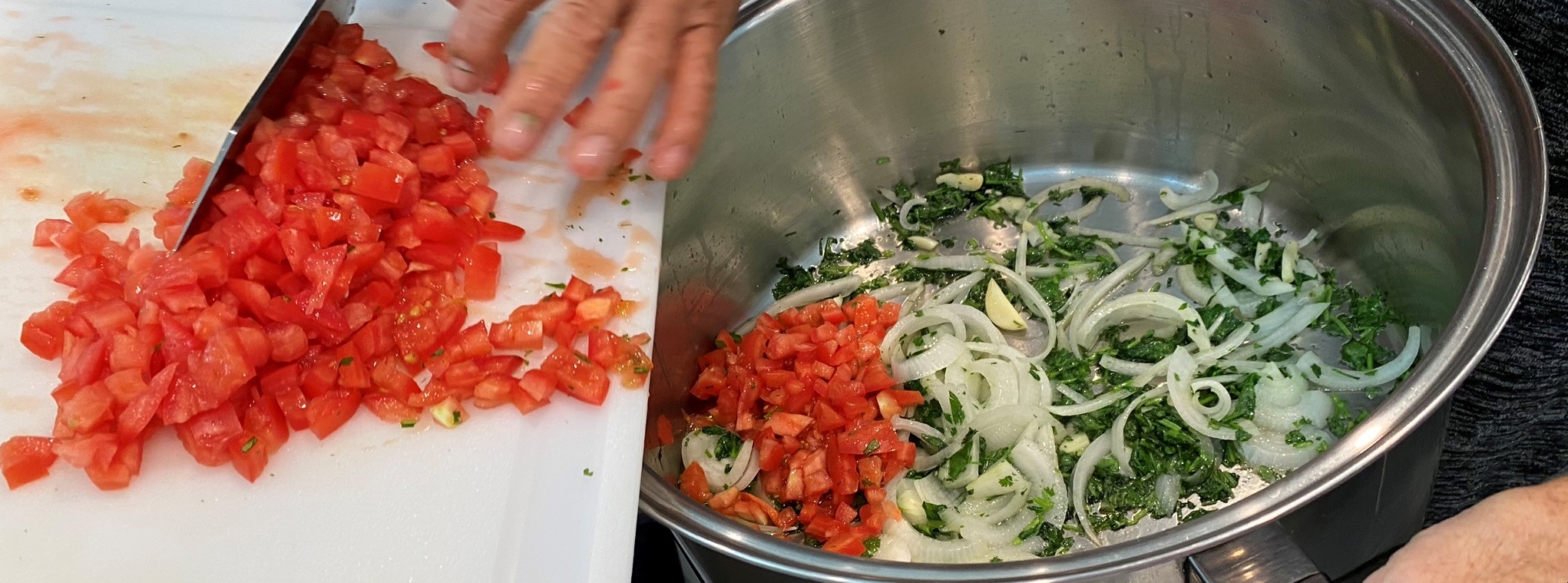 Fresh tomatoes, onions, and herbs being prepared for cooking