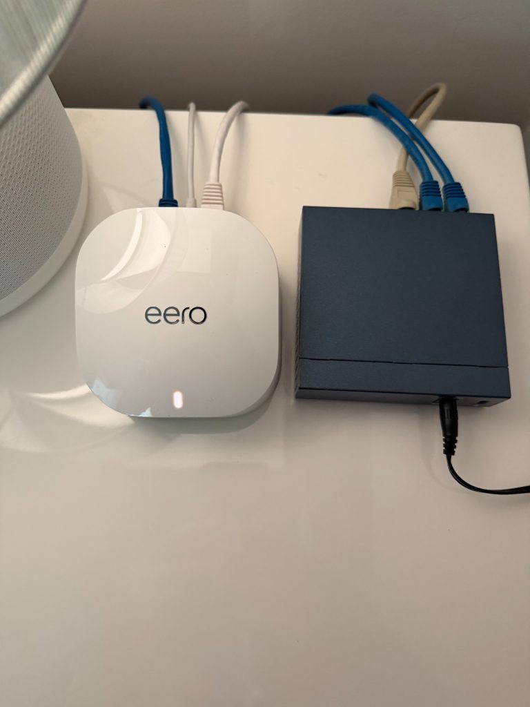 Upstairs-bedroom eero 6 and Ethernet switch beside an IKEA SYMFONISK lamp speaker.
